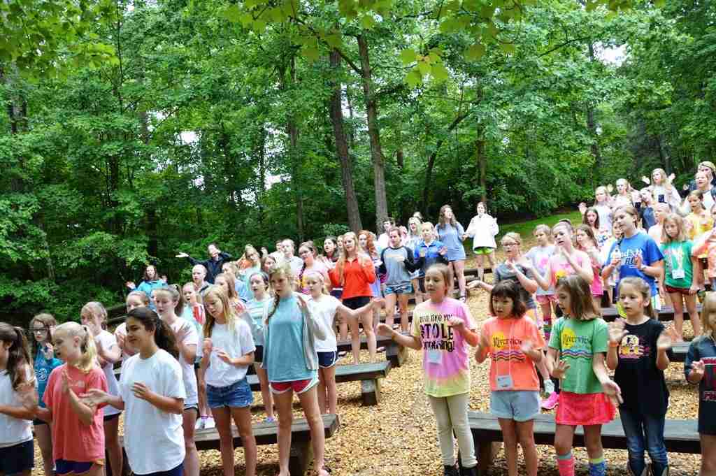 Campers singing together in the outdoor chapel in the woods