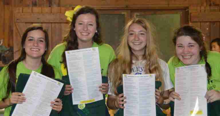 Four smiling ten-year campers holding their personal poems and blankets