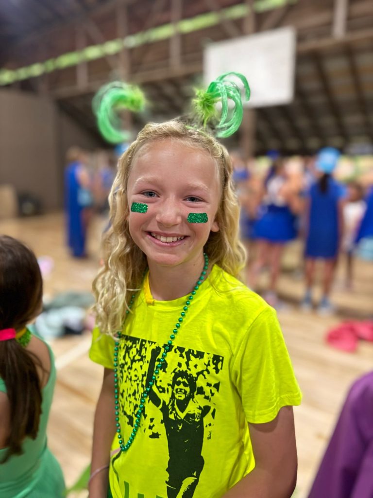 A smiling camper with face paint on team spirit night